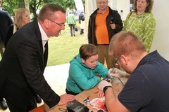 Die Airbrush-Tattoos, die die Evangelische Jugend auf der Kirchenmeile Jugendlichen "verpasst", sind heiß begehrt. Interessiert beobachtet Innenminister Boris Pistorius wie Christian Viebach aus Bockhorn das Kunstwerk auf den Arm sprüht.