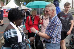 Auch zwei ökumenische Gäste aus der Partnerkirche aus Ghana sind beim Trachtenumzug bei den Kirchenleuten dabei: Presbyterin Gladys Feddy (hier im Bild) verteilt auch Segensbänder an Zaungäste und segnen sie. Viele bedanken sich sichtlich überrascht.